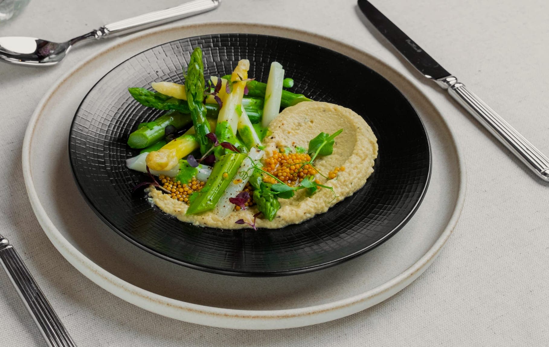 Asperges et houmous dressés sur assiette noire