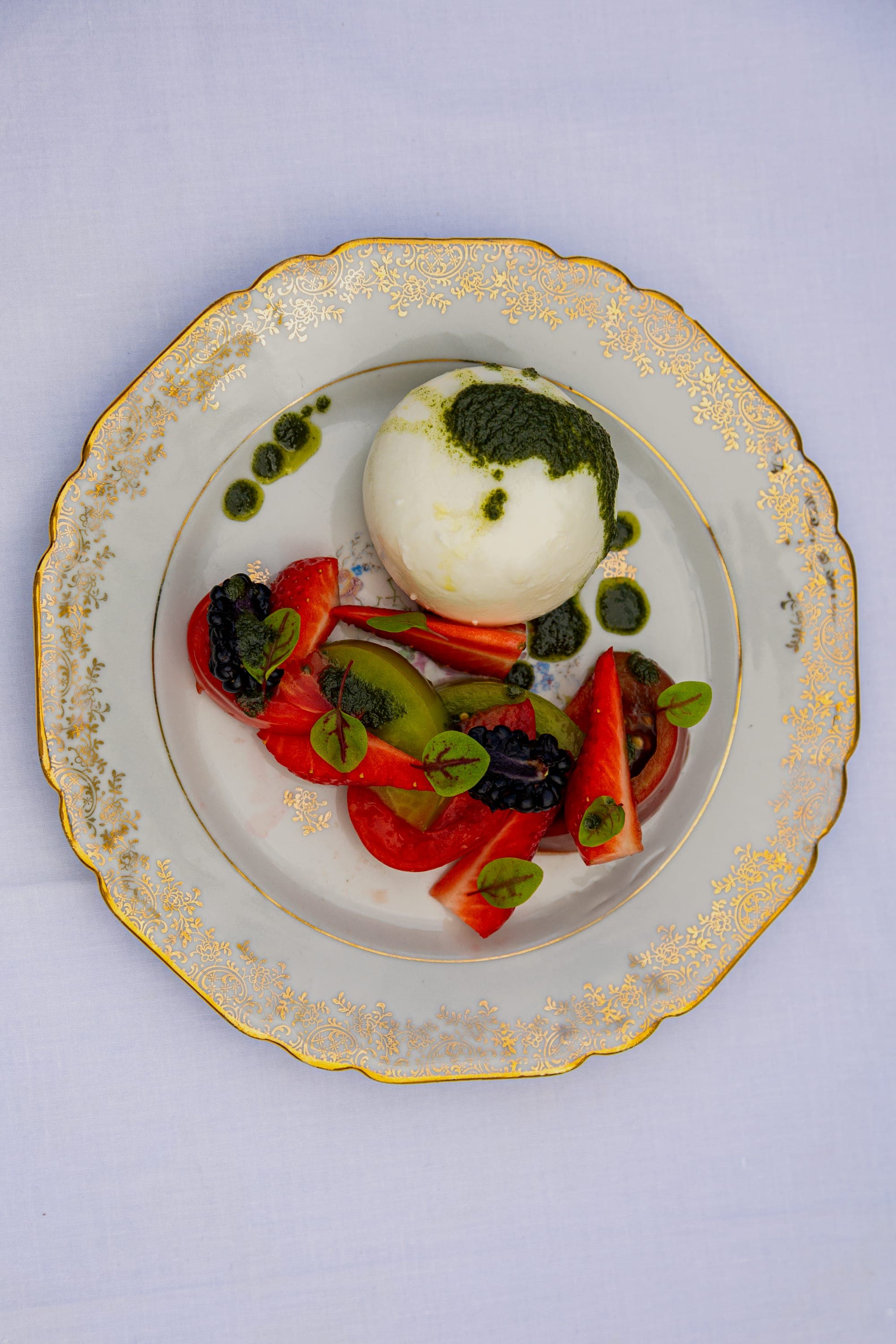 Burrata, tomates et herbes dressées sur assiette à filet doré